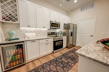 A kitchen with white cabinets and a marble countertop.